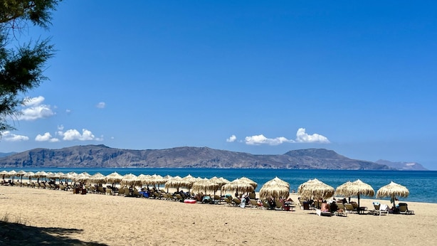 A beach with rows of sun loungers and thatched umbrellas under a clear sky. - Villa Artemis in Vrises (Apokoronas)
