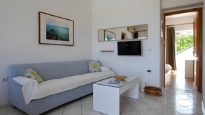 Un salon moderne avec un canapé bleu clair, une table basse blanche, un tableau encadré, un téléviseur à écran plat et un miroir au mur.