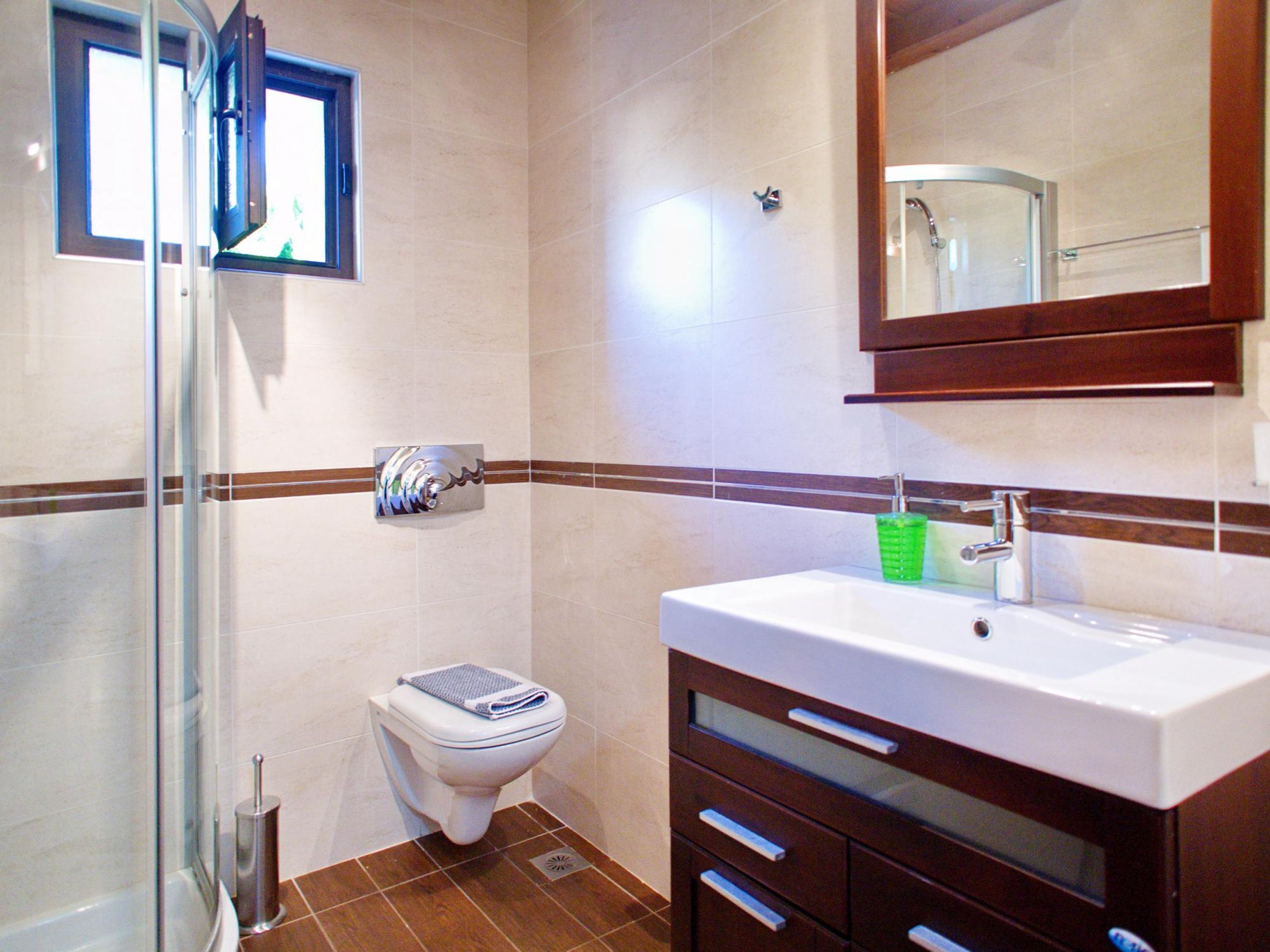 Une salle de bain avec une douche à parois de verre, des toilettes, un lavabo avec un miroir au-dessus et un porte-serviettes.