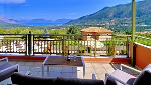 A terrace with a table and chairs, overlooking a scenic landscape with mountains and a body of water. - Villa Nireaus in Sami (Kefalonia)
