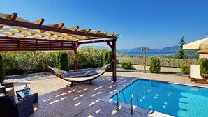A pool area with a hammock, outdoor furniture, and a pergola. - Villa Nireaus in Sami (Kefalonia)
