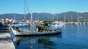 A marina with boats docked, a clear sky, and mountains in the background. - Villa Nireaus in Sami (Kefalonia)