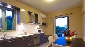 A modern kitchen with dark cabinets, a microwave, and a dining area with a table and chairs. - Villa Nireaus in Sami (Kefalonia)