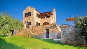 A stone building with a staircase leading to a door, surrounded by a well-maintained lawn and trees. - Villa Zara in Plaka With 3 Bedrooms and 3 Bathrooms (Apokoronas)