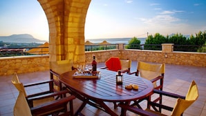 An outdoor dining area with stone arches, a round wooden table, and chairs. - Villa Zara in Plaka With 3 Bedrooms and 3 Bathrooms (Apokoronas)