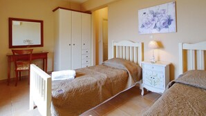 Une chambre à coucher comprenant un lit, une table de chevet, une commode, une chaise et un miroir.