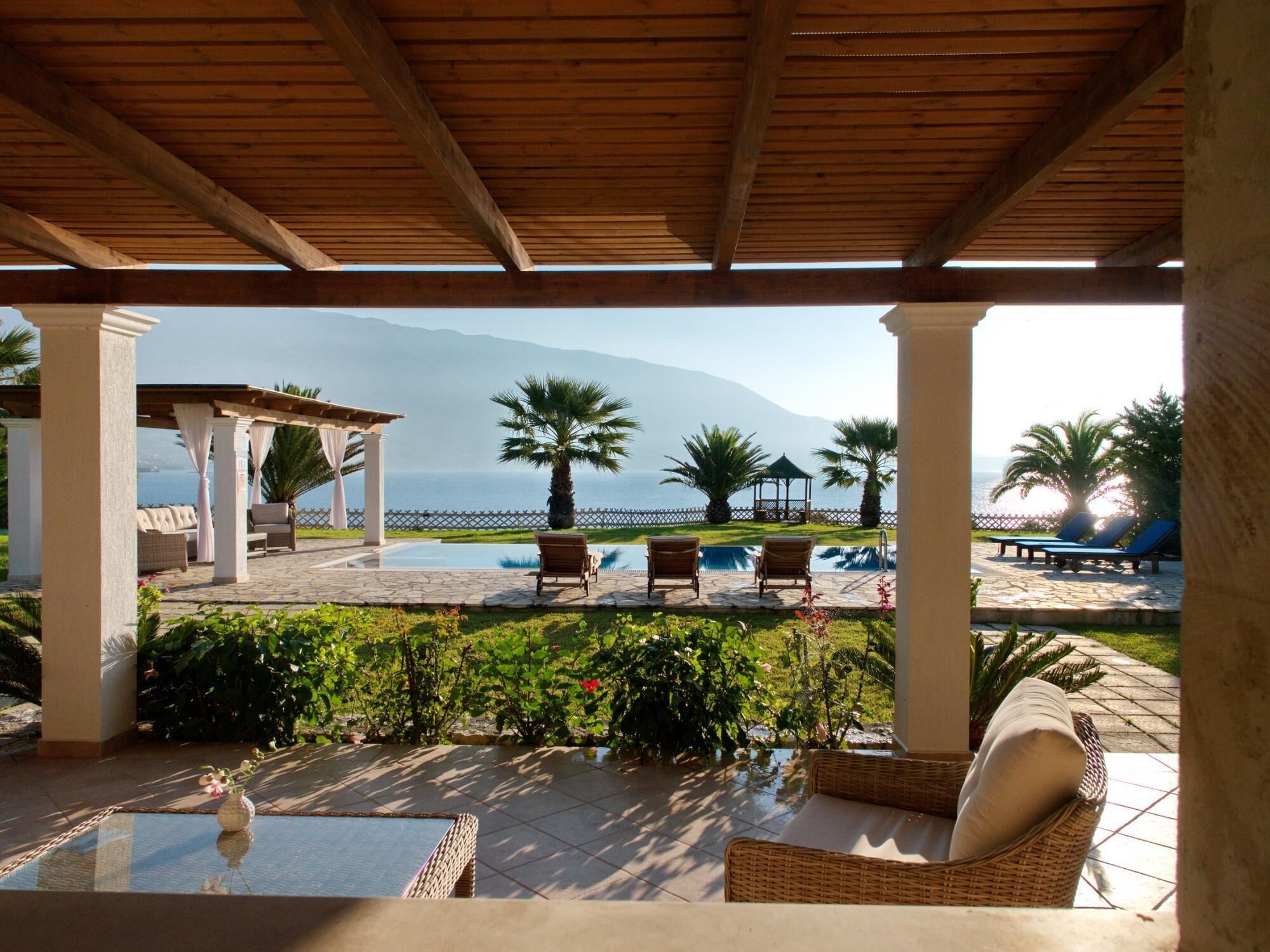 Un espacio al aire libre cubierto con piscina, sillones de descanso y vistas al mar y a las montañas.