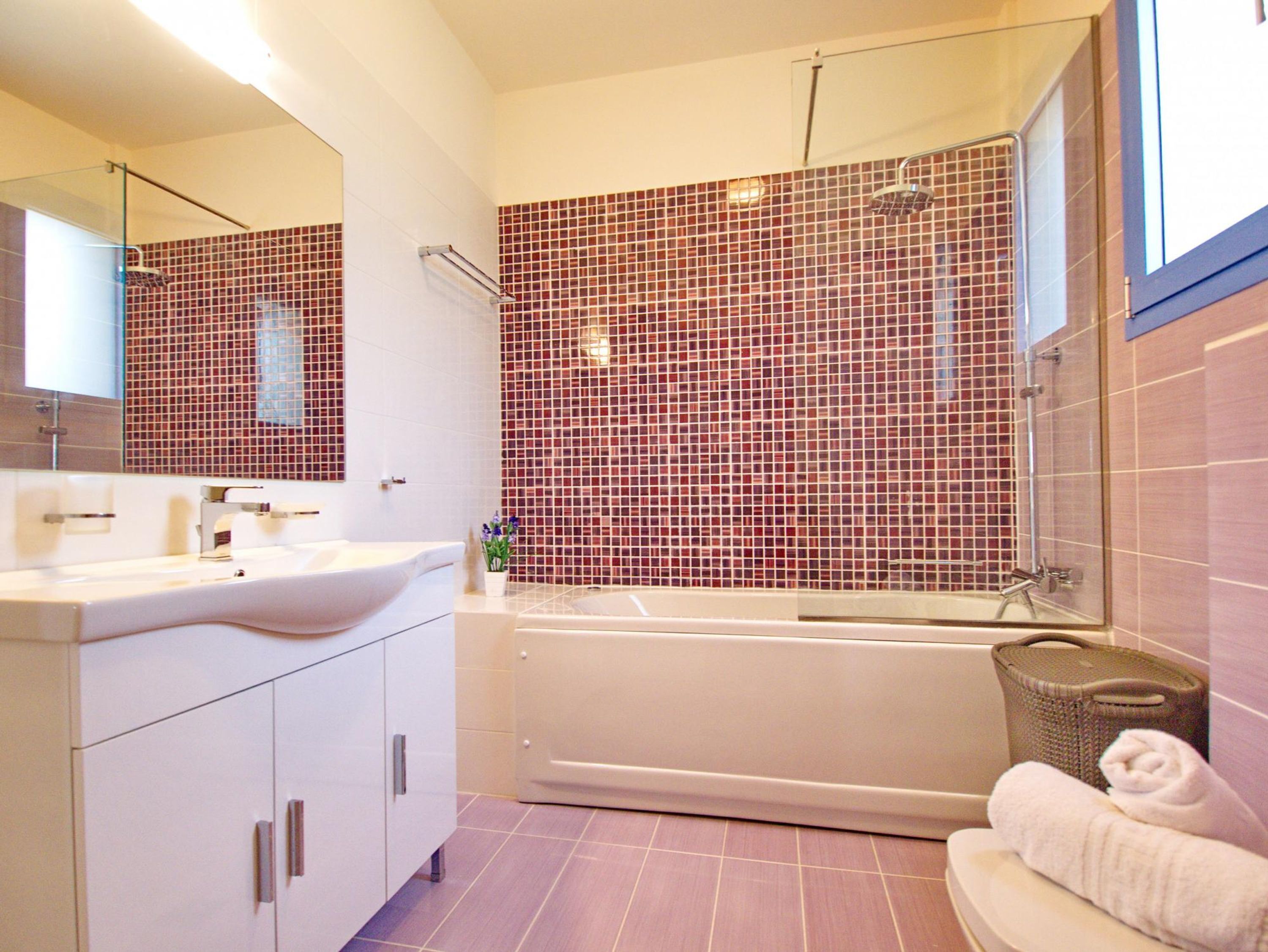 Une salle de bain moderne avec un meuble-lavabo blanc, un grand miroir, une baignoire et un espace douche.