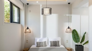 A modern bedroom with a large bed, two pendant lights, and a potted plant. - Villa Anemi in Sternes (Chania)