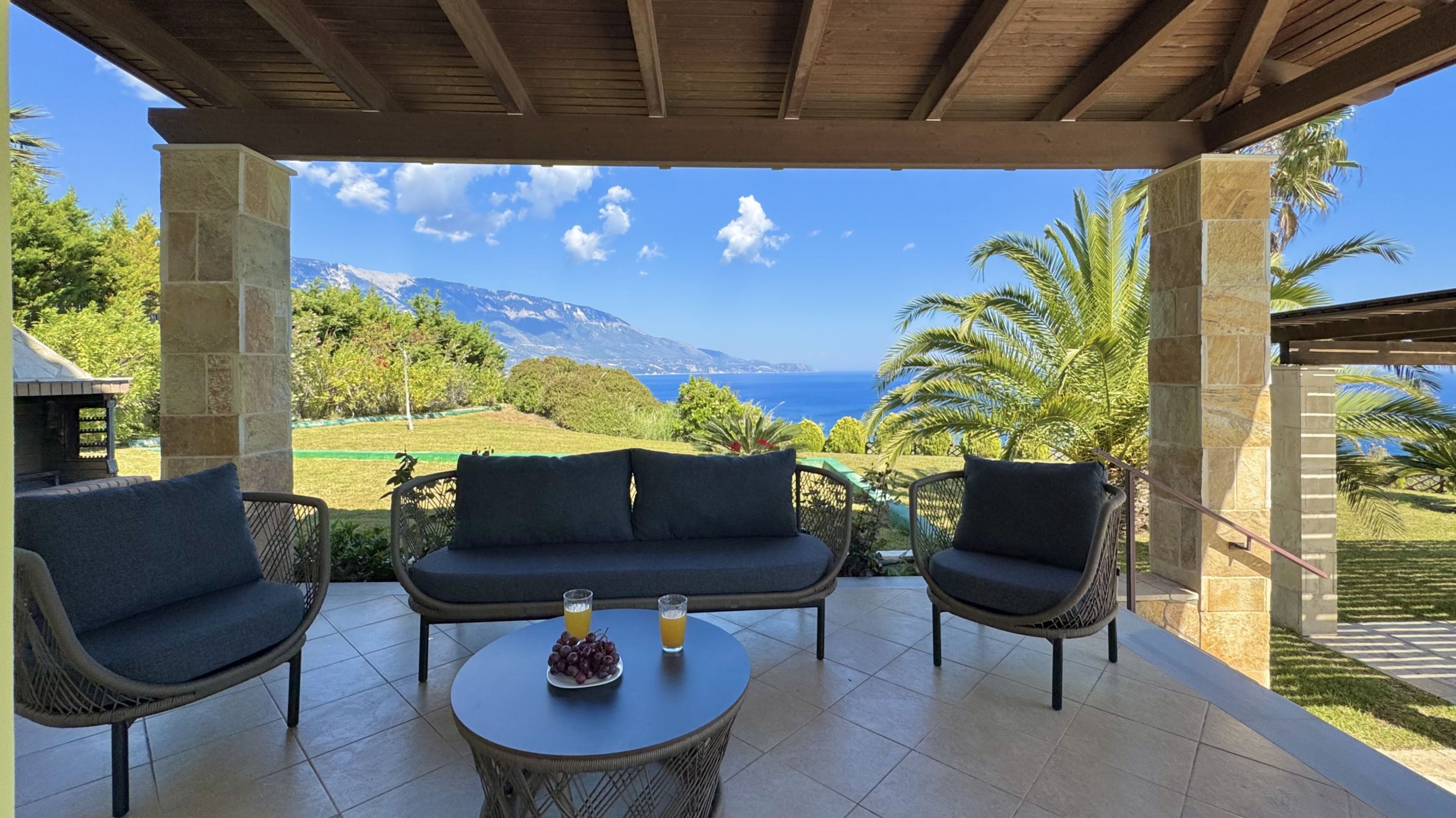A covered outdoor seating area with a view of the sea and mountains.