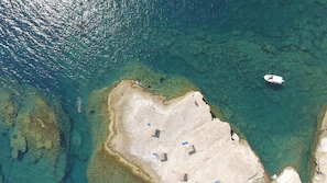 An aerial view of a beach with clear waters, a boat, and several umbrellas. - Villa Dimitra in Spartia (Kefalonia)