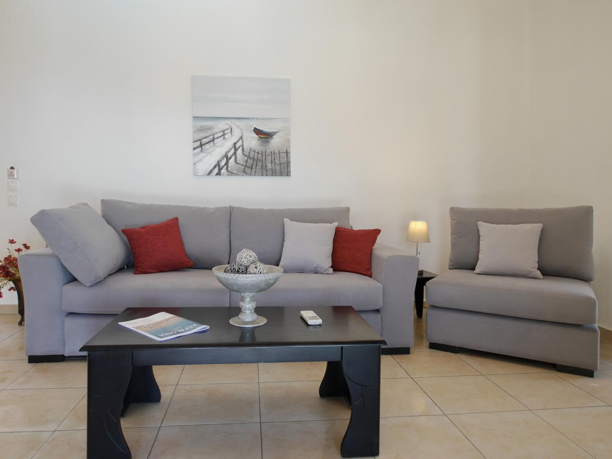 Un salon avec deux canapés gris, une table basse et un tableau accroché au mur.