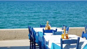 Mesa y sillas junto al mar, cubiertas con un mantel y saleros, con vista al océano.