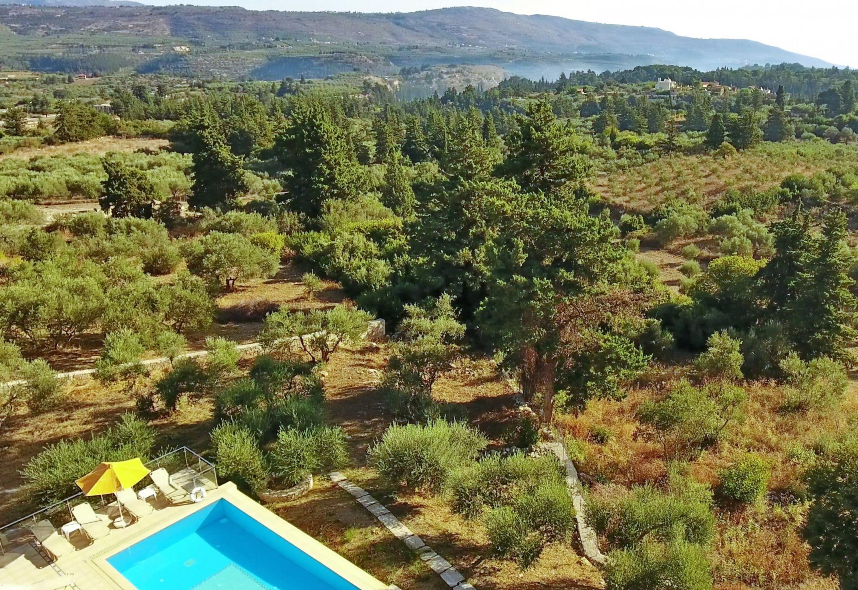 A pool area with a clear view of the surrounding landscape, including trees and distant hills.