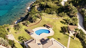 An aerial view of a coastal property with a swimming pool, palm trees, and a yacht in the water. - Villa Alexandros in Spartia (Kefalonia)