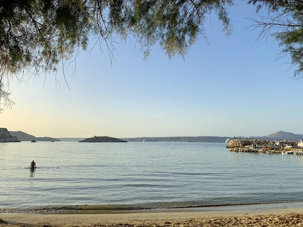 Wade into the calm waters of this pristine coastline, where a rocky outcrop meets the sea.