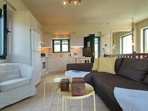 Cozy living space with a kitchenette, sofa, chair, and table, perfect for a compact retreat.