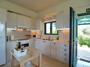 Enjoy cooking in this well-equipped kitchen with a microwave, stainless steel sink, and wooden table.