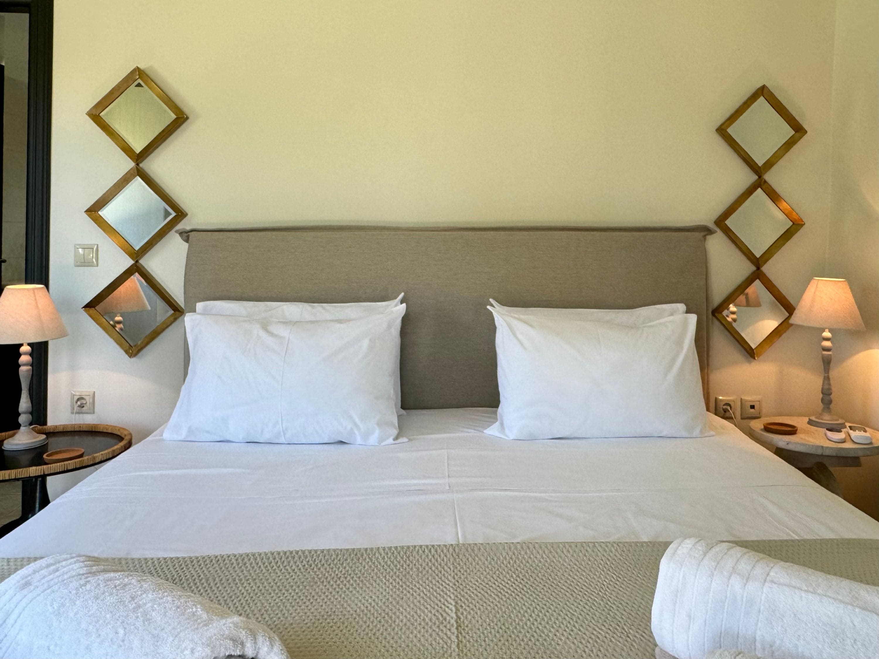 A hotel room with a bed, two bedside lamps, and a wall-mounted mirror.