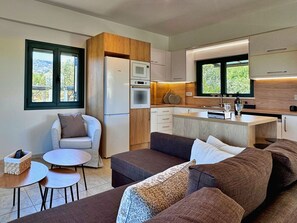 Un espacio habitable compacto con kitchenette, un sofá, una pequeña mesa de comedor y una ventana con vistas a zonas verdes.