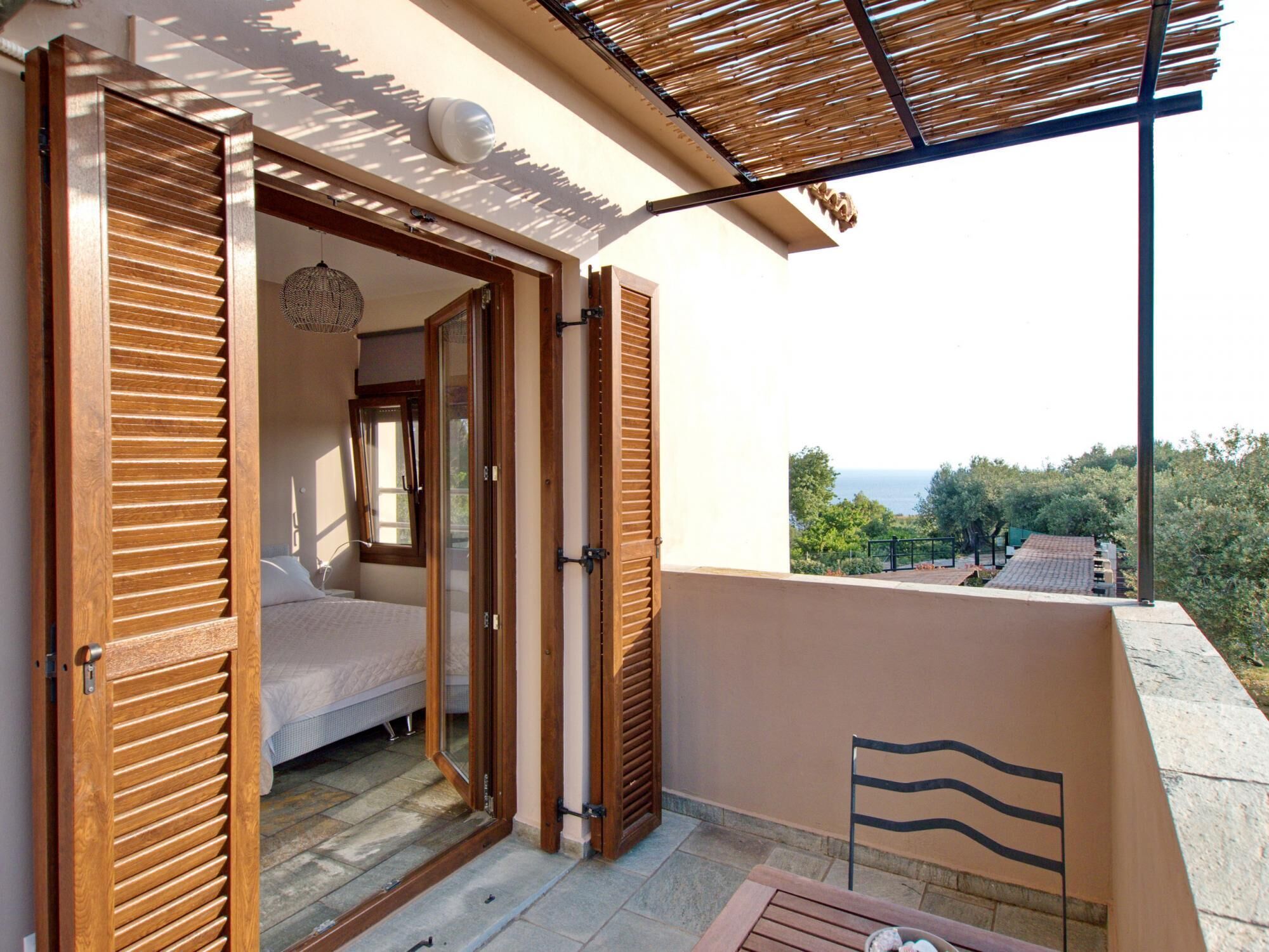 Un balcon avec un lit, une vue sur la mer et une pergola en bois.