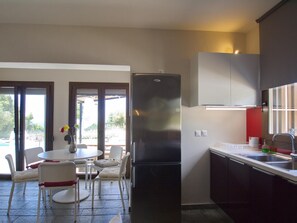A modern kitchen with a stainless steel refrigerator, white cabinets, and a dining area with a table and chairs.