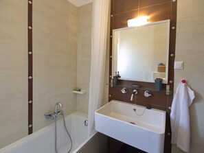 A bathroom with a bathtub, a sink, and a mirror.
