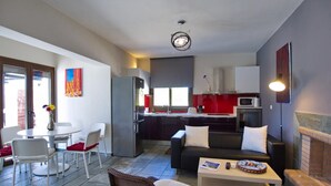 Et moderne køkken med køleskab, mikroovn og komfur. Der er et spiseområde med et bord og stole, samt en opholdsstue med sofa og sofabord.