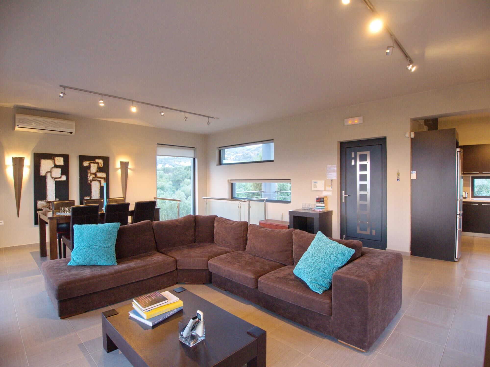 A modern living room with a sectional sofa, a coffee table, and a dining area with a table and chairs.