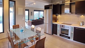 Una cocina moderna con una mesa de comedor de vidrio, electrodomésticos de acero inoxidable y vistas al área de estar.