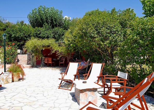 An outdoor seating area with stone flooring and wooden chairs.