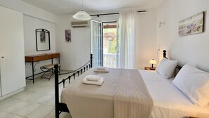 A bedroom with a bed, a desk, a chair, a lamp, and a view of the outdoors. - Villa Ermis in Spartia (Kefalonia)