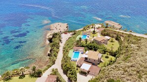 An aerial view of a coastal property with a swimming pool, multiple buildings, and a beach. - Villa Penelope in Spartia (Kefalonia)