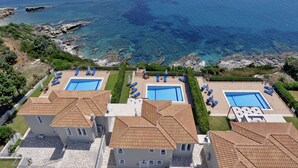 Un hotel frente al mar con dos piscinas, tejados de terracota y vistas al océano.