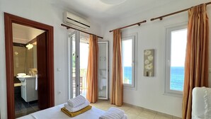 Una habitación de hotel con cama, baño y vista al mar.