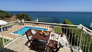 Un balcón con piscina, mobiliario exterior y vista al mar.