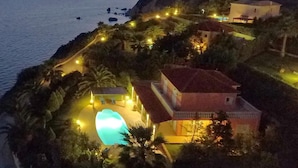 A coastal property with a swimming pool, multiple buildings, and a view of the sea at sunset. - Villa Kephalos in Spartia (Kefalonia)