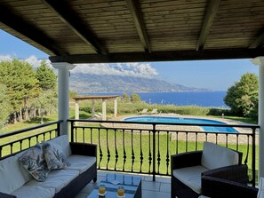 A covered outdoor area with a pool, seating, and a view of the sea. - Villa Neptune in Spartia (Kefalonia)