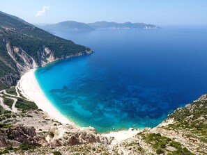 A coastal landscape with a clear blue sea, a sandy beach, and rocky terrain. - Villa Neptune in Spartia (Kefalonia)