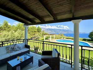 A covered outdoor seating area with a pool, a sofa, and a table. - Villa Neptune in Spartia (Kefalonia)