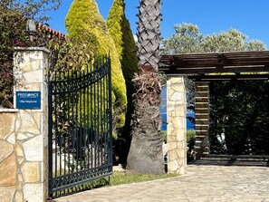 A gated entrance with a stone pillar, a sign for 'Freelance Holiday Villa Rentals,' and a pergola structure. - Villa Neptune in Spartia (Kefalonia)