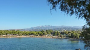 A coastal view with clear water, rocky outcrops, and a distant mountain range. - Maros Spitaki in Varipetro (Chania)