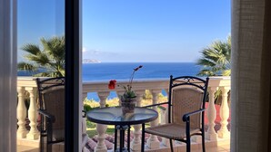 A balcony with a table and chairs, overlooking a coastal view with palm trees and a clear sky. - Villa Dionysos in Spartia (Kefalonia)