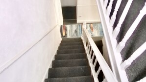 Un escalier avec des balustrades blanches et une moquette sombre.