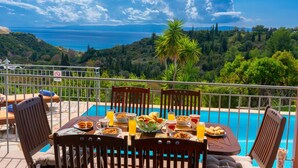 A dining table with breakfast items and a pool view. - Villa Mounda Apollon (Kefalonia)