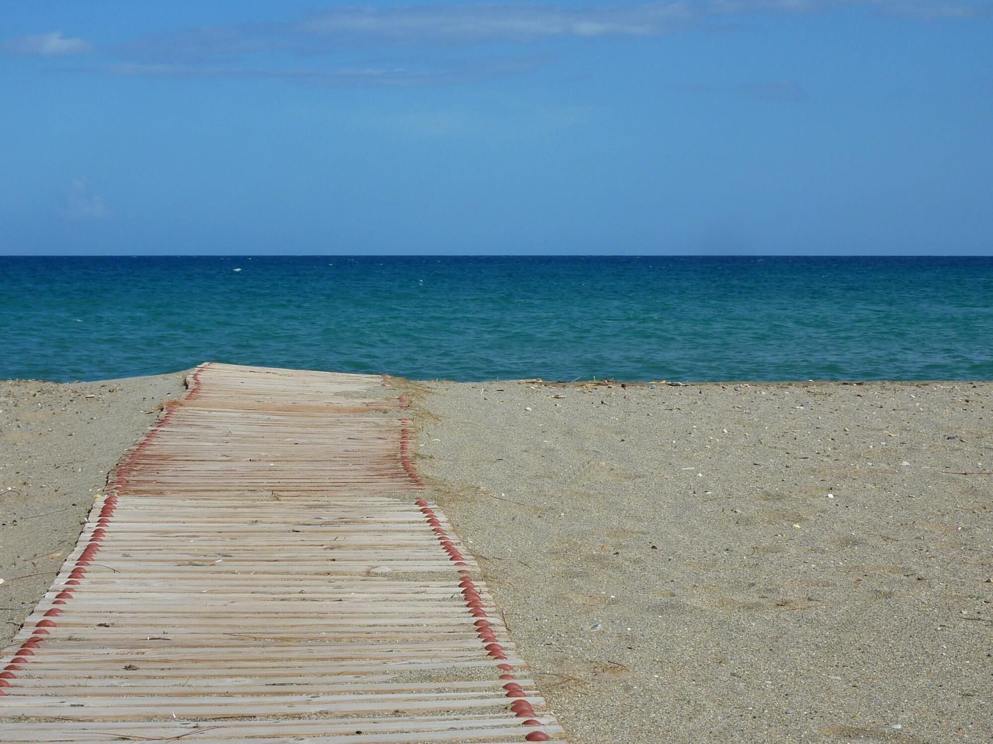 Un muelle de madera que conduce a una playa con aguas azules y cristalinas.