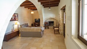 A spacious living room with a fireplace, wooden beams, and a television. - Villa Argiro in Plaka (Apokoronas)