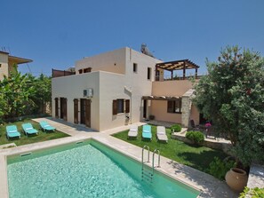Uma casa moderna de dois andares com piscina, área de estar externa e pérgola.