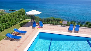 A pool area with lounge chairs and a view of the ocean. - Villa Seagull in Skala (Kefalonia)