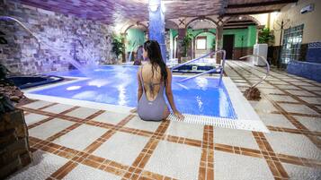 Relax by the pool, surrounded by lush greenery and a soothing water feature.